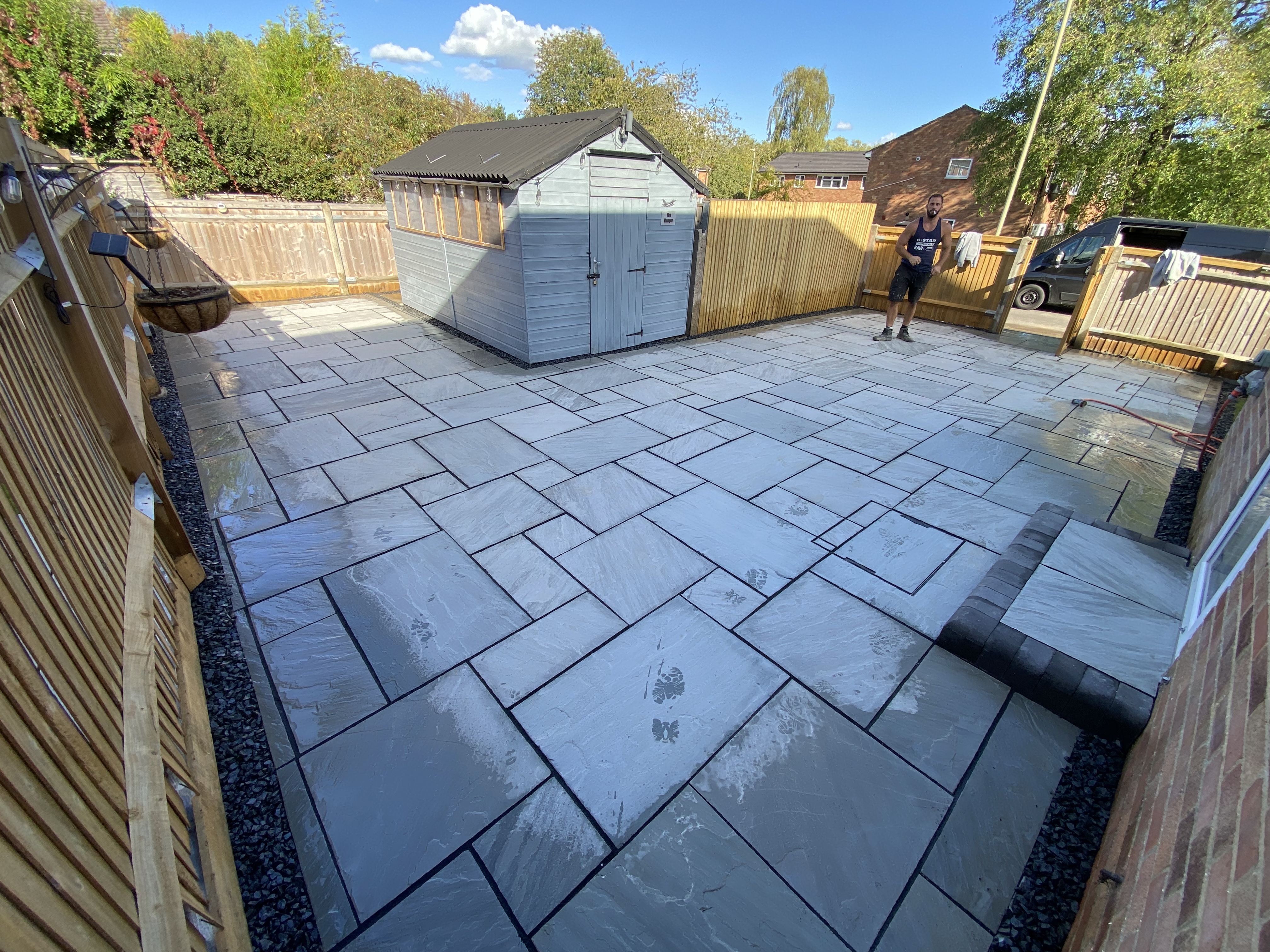Finished grey paved garden patio with timber fencing and painted shed in a Hampshire garden.
